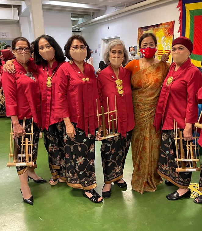 Volunteers in Nepali dress at a community festival stall, presenting cultural artefacts.