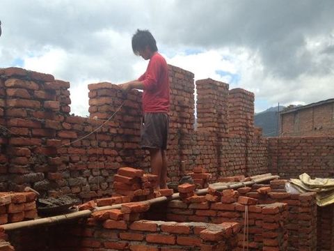 A mason standing on the half-built brick walls of the new girls’ bathroom block.