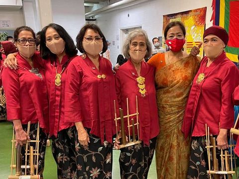 Volunteers in Nepali dress at a community festival stall, presenting cultural artefacts.