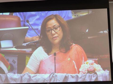 Prabha Bhattarai Deuja speaking, shown on a large presentation screen.