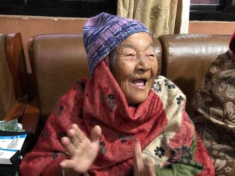 An elderly resident of Mudita Home laughing with her hands raised.