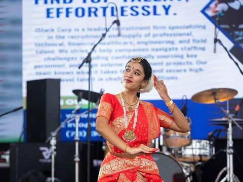 A classical Nepali dancer in a red costume performing on the festival stage.
