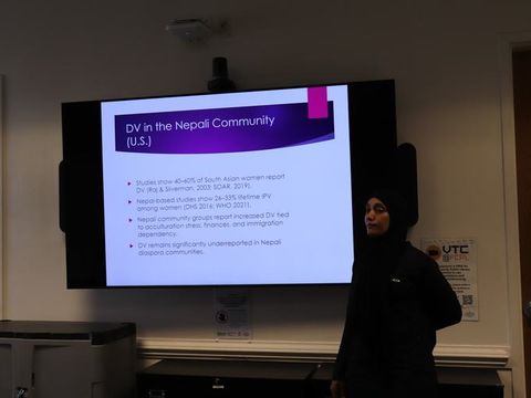 A presenter addressing attendees in front of a slide about resources for the Nepali community.
