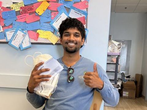 A young donor smiling in the donation chair, giving a thumbs up.