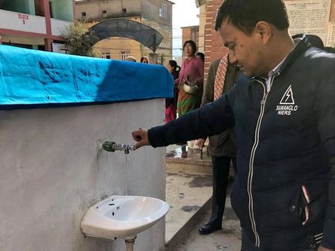 A man turning on the tap of the newly installed washbasin and water fountain.