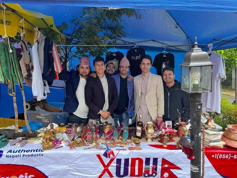 Volunteers behind a Nepali crafts and food stall under a tent at Passport DC.