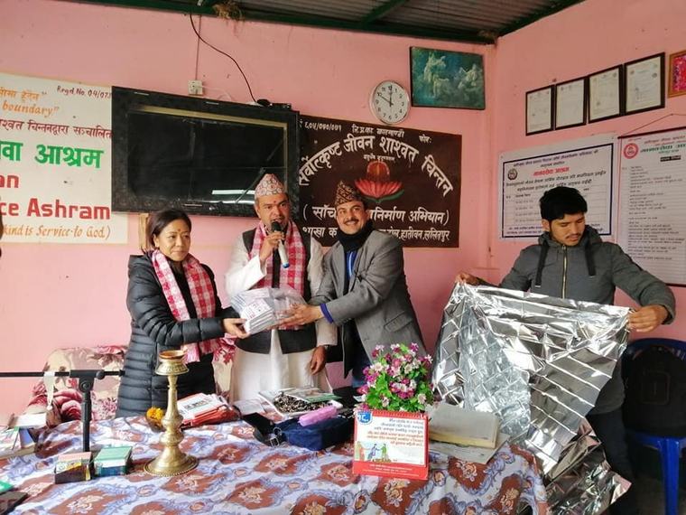Volunteers unpacking emergency blankets onto a bed at Manavsewa Ashram.