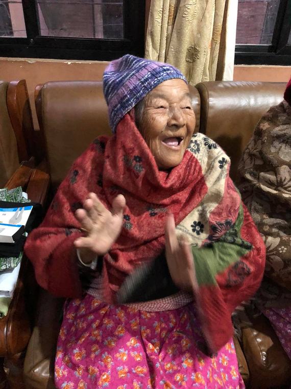 An elderly resident of Mudita Home laughing with her hands raised.