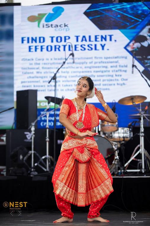 A classical Nepali dancer in a red costume performing on the festival stage.