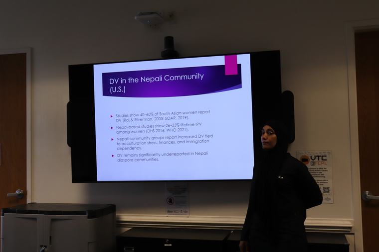 A presenter addressing attendees in front of a slide about resources for the Nepali community.