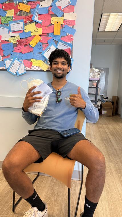 A young donor smiling in the donation chair, giving a thumbs up.