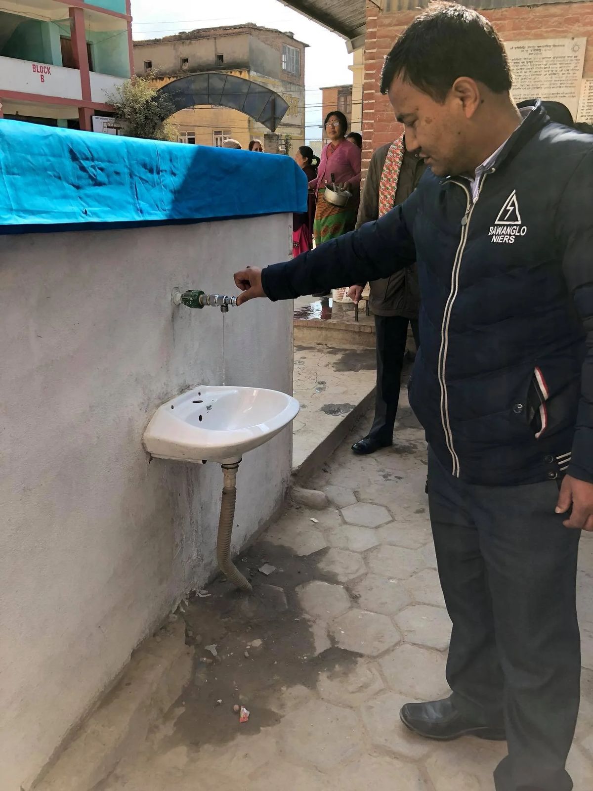 A man turning on the tap of the newly installed washbasin and water fountain.